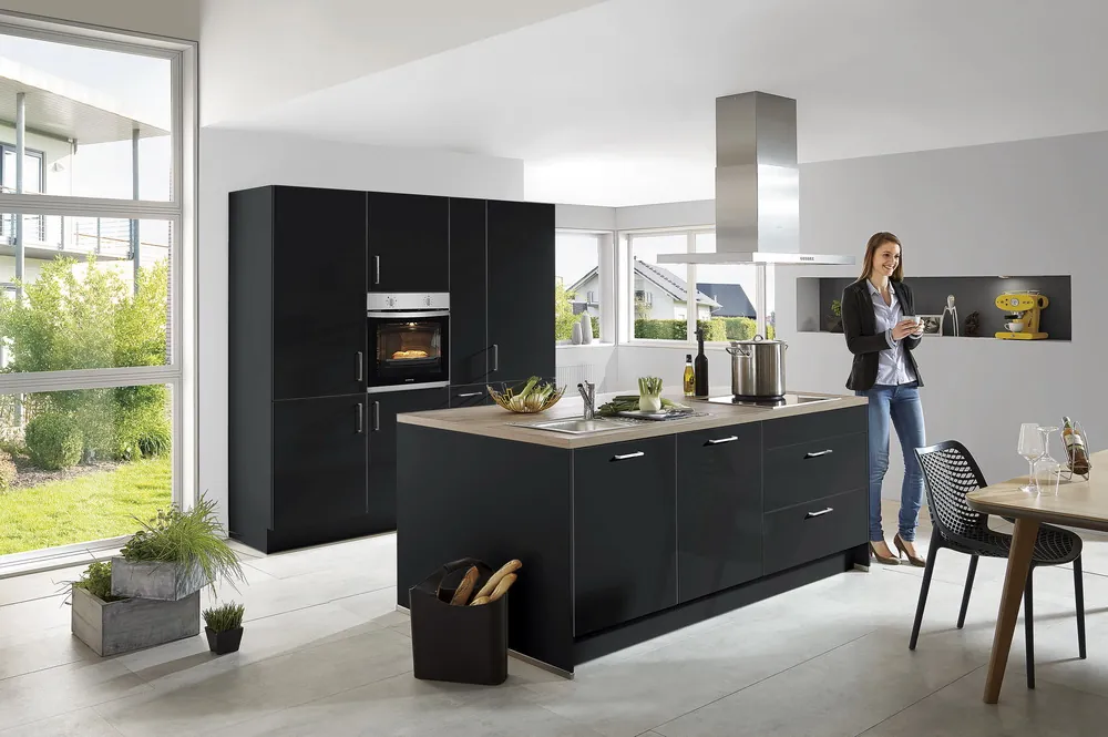 Schwarze Küche in Mattoptik mit Kochinsel und Holzplatte vor großer Fensterfront